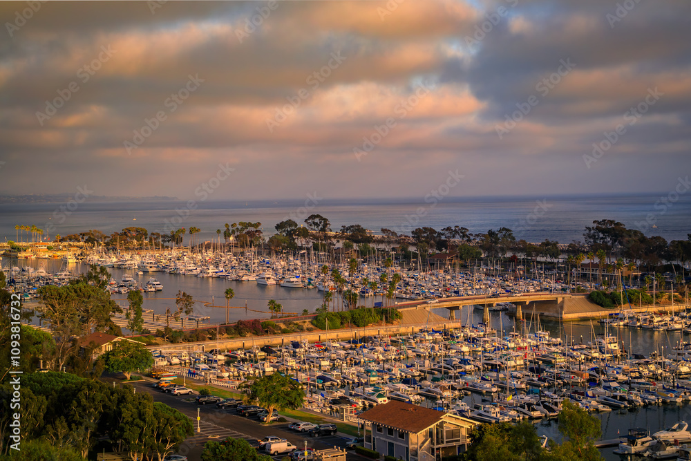 Fototapeta premium Sunset over luxury homes, yachts, and boats in Dana Point harbor, Orange County in Southern California on a cloudy day