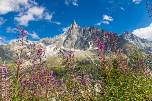 Petit Dru granite mountain wall and summit in Chamonix valley, french Alps. Prominent mountain peak in the Alps, stunning landscape view of the rocky peak covered with clouds, snow and ice