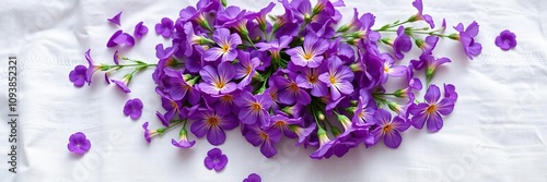 A cluster of vibrant purple flowers scattered on a soft white linen fabric with subtle texture and pattern, elegance, sophistication