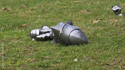 Fotografie Medieval steel helmet and gauntlets resting on grass, suggesting a historical reenactment or display