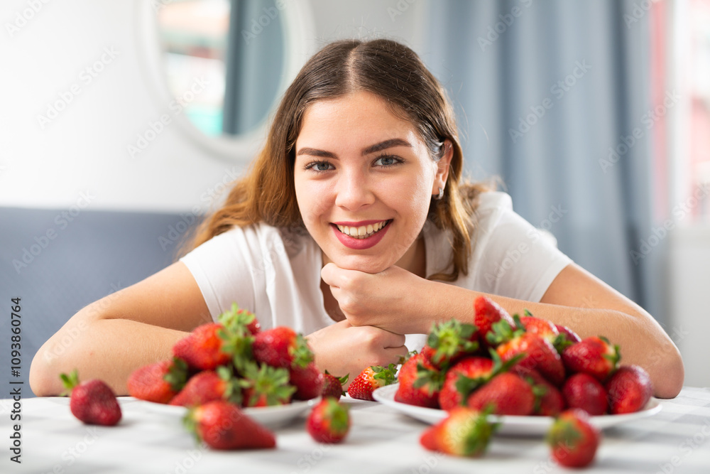 Happy girl holding heap of strawberries in the room at home Happy girl holding heap of strawberries in the room at home