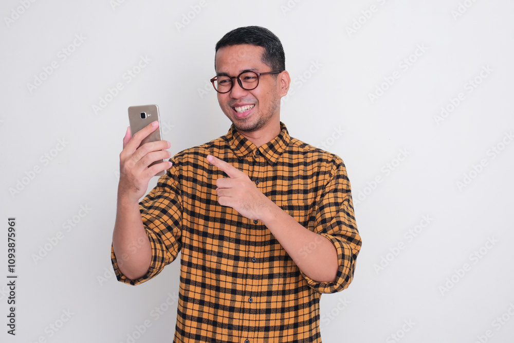 A man staring and pointing at his mobile phone with happy expression A man staring and pointing at his mobile phone with happy expression