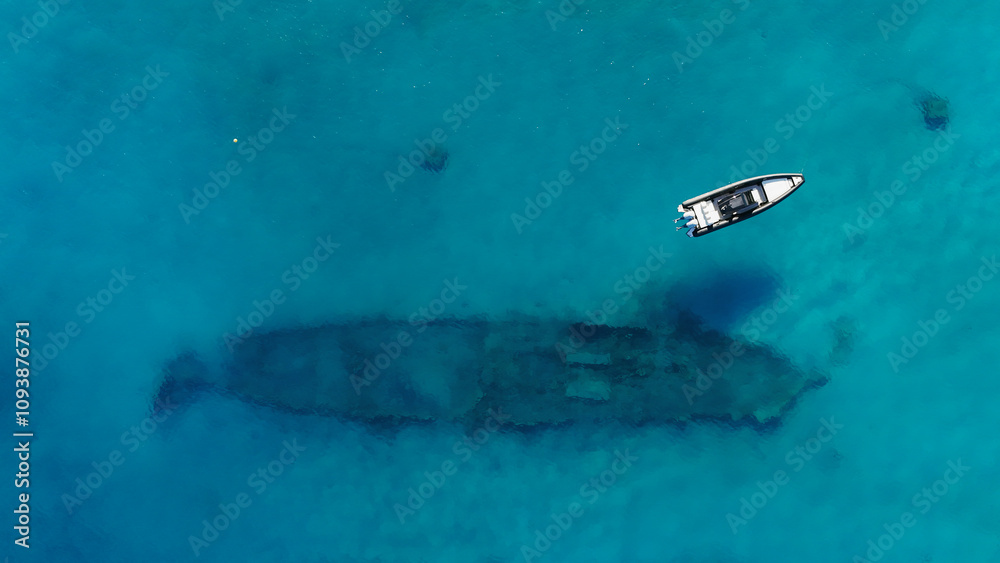 A sports boat is anchored in the middle of the sea with turquoise water from the top view of a drone A sports boat is anchored in the middle of the sea with turquoise water from the top view of a drone