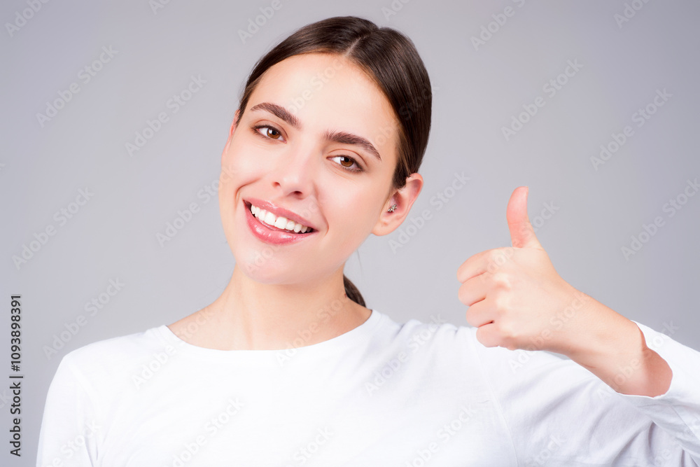 Closeup portrait of Young Woman show thumb up isolated on gray background. Female hand showing thumb up. A hand giving a thumbs up. Happy Woman with thumb up. Closeup portrait of Young Woman show thumb up isolated on gray background. Female hand showing thumb up. A hand giving a thumbs up. Happy Woman with thumb up.