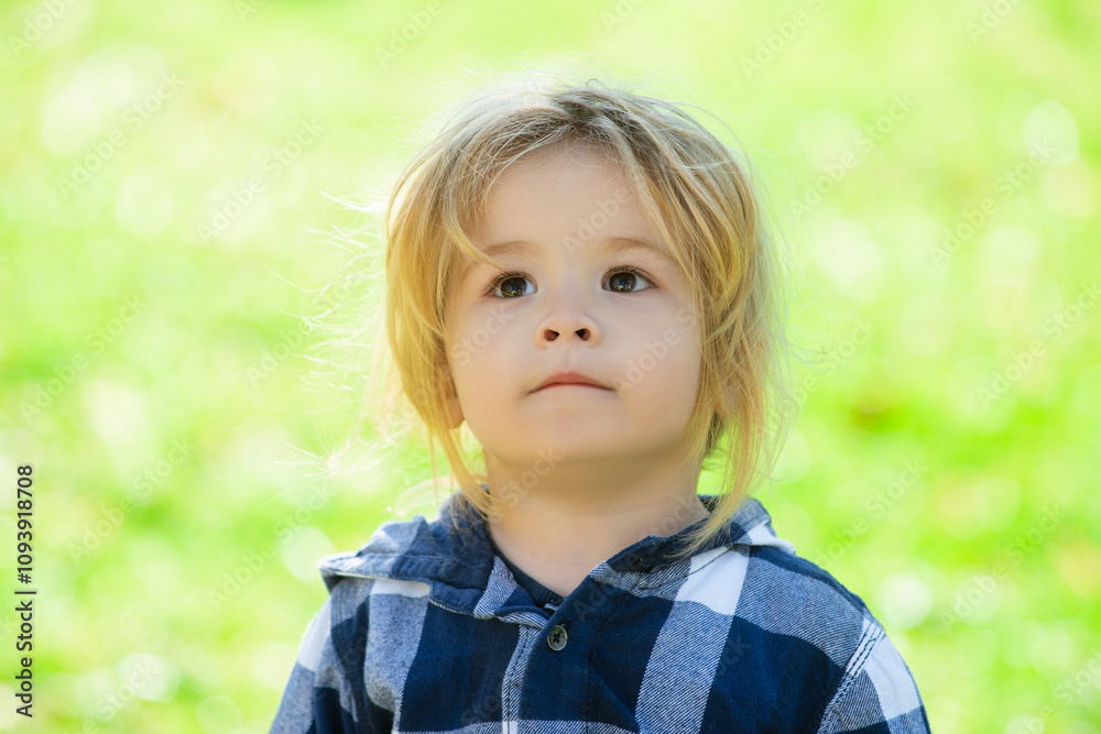 Portrait of cute little caucasian boy having fun in garden. Child on green grass lawn during walk in yard. Happy childhood and baby healthcare.