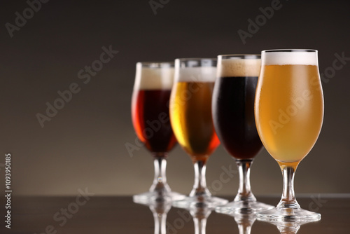 Glasses with different types of beer on mirror surface, closeup. Space for text