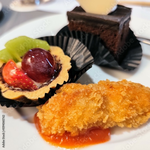 A plate featuring a dessert with slices of srikaya fruit, strawberries and grapes along with a piece of cake and chicken nuggets, displays a delicious culinary dish photo