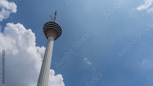 Photography A tall TV tower on a background of blue sky and clouds