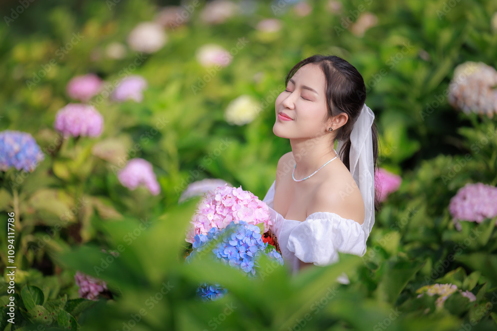 Beautiful woman in white weding dress in colorful hydrangea flowers field, portrait of enjoying and relaxtion Beautiful woman in white weding dress in colorful hydrangea flowers field, portrait of enjoying and relaxtion
