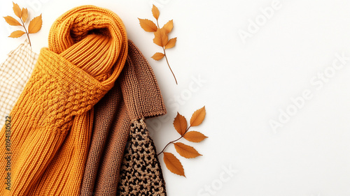 Cozy knitted scarf and warm fabrics with autumn leaves photo