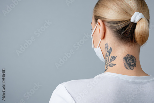 Health conscious individual wearing mask showcasing neck tattoo in a minimalistic indoor setting emphasizing personal style and safety photo