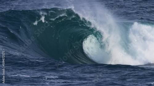 Large wave barrels, foam ball spraying out from the curl in powerful, slow motion detail photo