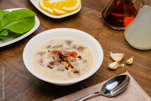 Tripe soup in a white bowl, garnished with vinegar and lemon. Turkish cuisine Soup, traditional healing soup made with tripe.