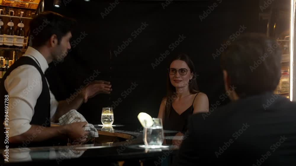 Focusing on beautiful woman guest sitting in special drink gin fizz at luxurious counter bar at vibrant nightlife party atmosphere. Smart bartender wiping glass while talking with customer. Vinosity. Focusing on beautiful woman guest sitting in special drink gin fizz at luxurious counter bar at vibrant nightlife party atmosphere. Smart bartender wiping glass while talking with customer. Vinosity.
