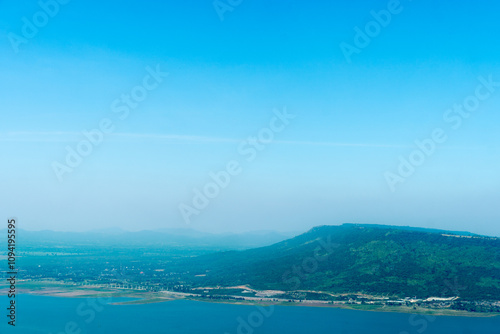 Landscape view of the mountain range in a faint fog at the edge of the Lam Taklong reservoir. Under view clear blue sky.