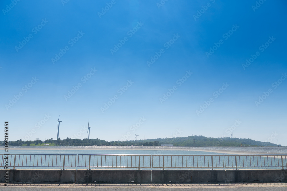 Horizontal view of asphalt road with cement and Stainless steel road railing. Background of Reservoir of Khao Yai Thieng Windmill Nakhon Ratchasima Thailand. Horizontal view of asphalt road with cement and Stainless steel road railing. Background of Reservoir of Khao Yai Thieng Windmill Nakhon Ratchasima Thailand.