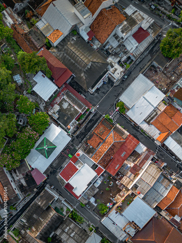 Aerial photograph showcasing a densely populated urban neighborhood. The rooftops feature a mix of colors and materials, highlighting an intricate street layout
