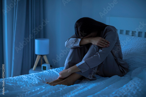 Suffer from depression, mental health problem. Young woman sitting on bed at night feeling depressed or can not sleep