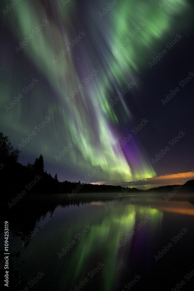 Burst of northern lights over a lake with reflection, Norway Burst of northern lights over a lake with reflection, Norway