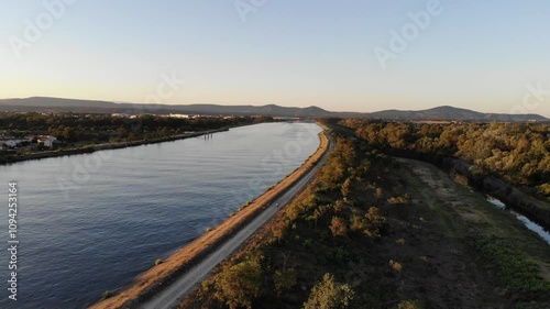 Wallpaper Mural Aerial footage of the Rhine River in an industrial area with a bridge at dawn, showcasing the serene morning light reflecting on the water and structures. Torontodigital.ca