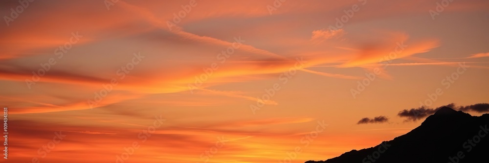 Obraz premium The silhouette of a mountain peak against a vibrant sunset with clouds drifting across the horizon, serene, sunsets, peaceful