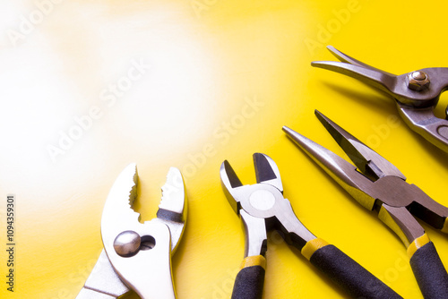 Pliers, nippers and metal scissors on a yellow background.
