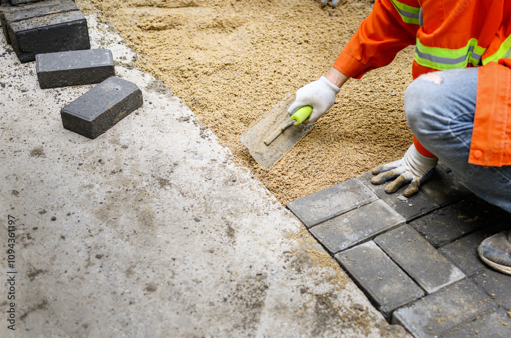 Worker laying brick pavers on the sidewalk. Road paving and repairing project.