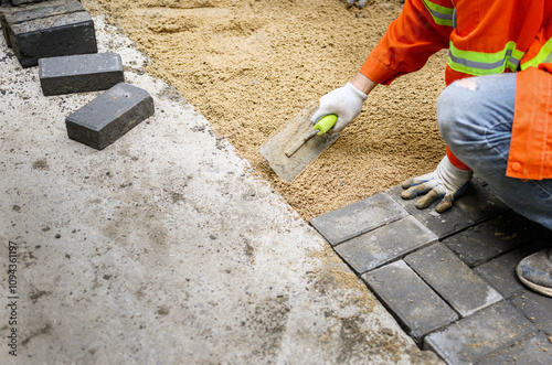 Obraz na płótnie Worker laying brick pavers on the sidewalk. Road paving and repairing project. w salonie