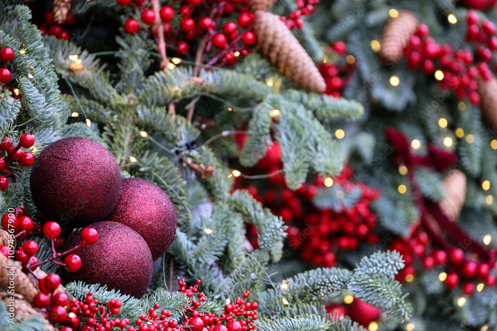New Year background, Christmas tree branches with red balls and cones on blurred lights background New Year background, Christmas tree branches with red balls and cones on blurred lights background