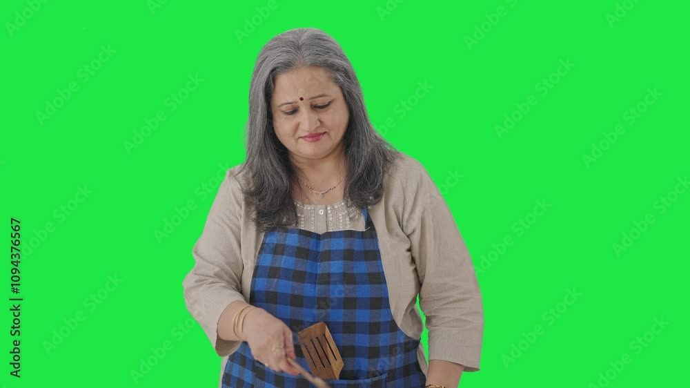 Disgusted Indian aged housewife cooking food Green screen Disgusted Indian aged housewife cooking food Green screen