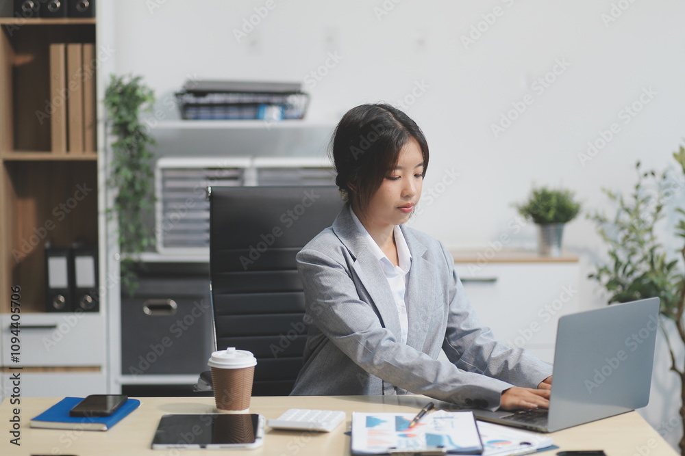 Successful Asian businesswoman smiling using laptop computer and holding coffee cup at office. Confident Asia businesswoman sitting happily in the office. Successful Asian businesswoman smiling using laptop computer and holding coffee cup at office. Confident Asia businesswoman sitting happily in the office.