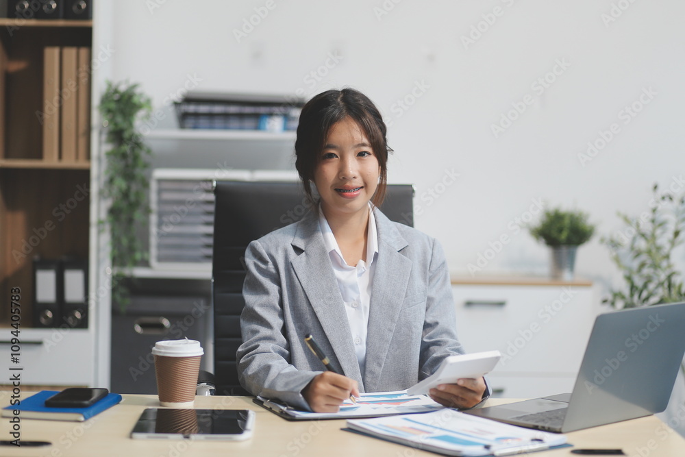 Successful Asian businesswoman smiling using laptop computer and holding coffee cup at office. Confident Asia businesswoman sitting happily in the office. Successful Asian businesswoman smiling using laptop computer and holding coffee cup at office. Confident Asia businesswoman sitting happily in the office.
