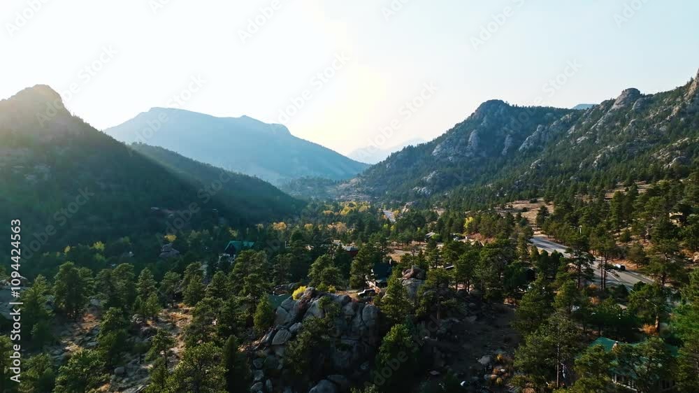 Aerial ascend over mountains and rocky boulders of Estes Park, Colorado, with vibrant autumn colors and sunflare over valley roads and mountain ridges Aerial ascend over mountains and rocky boulders of Estes Park, Colorado, with vibrant autumn colors and sunflare over valley roads and mountain ridges