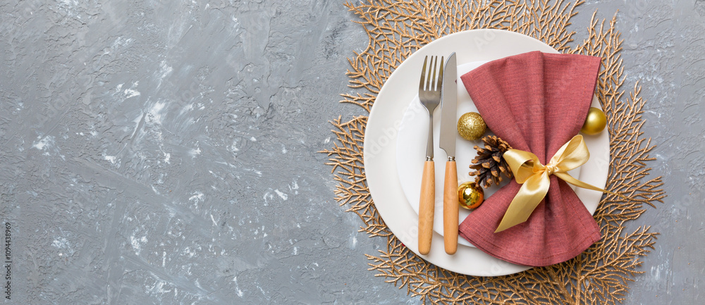 Naklejka premium Christmas table place setting with christmas decor and plates, kine, fork and spoon. Christmas holiday background. Top view with copy space