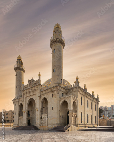 The majestic Taza Pir Mosque in Baku, Azerbaijan is captured in a sunset shot. The mosque features intricate architecture and twin minarets. The scene is set against a peaceful early evening sky photo