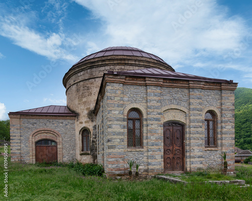 The Round Temple, also known as Three Saints Church, located near the Palace of Shaki Khans in Shaki, Azerbaijan, set against a backdrop of a clear blue sky