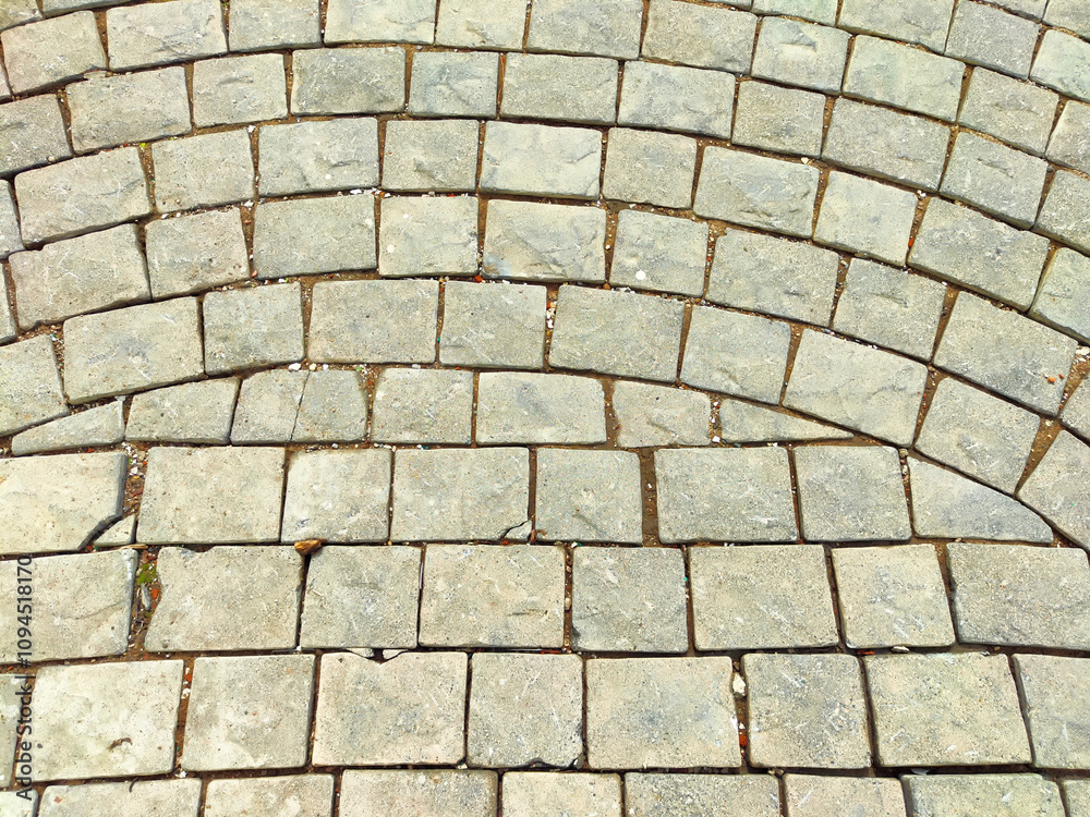 Paved walkway with curved pattern and textured stone blocks in a serene outdoor setting on a sunny day Paved walkway with curved pattern and textured stone blocks in a serene outdoor setting on a sunny day