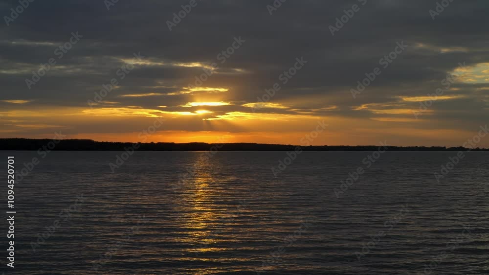 A beautiful reflection of the bright orange sunset over the water surface of Lake Tisza in Abadszalok, Hungary. A beautiful reflection of the bright orange sunset over the water surface of Lake Tisza in Abadszalok, Hungary.