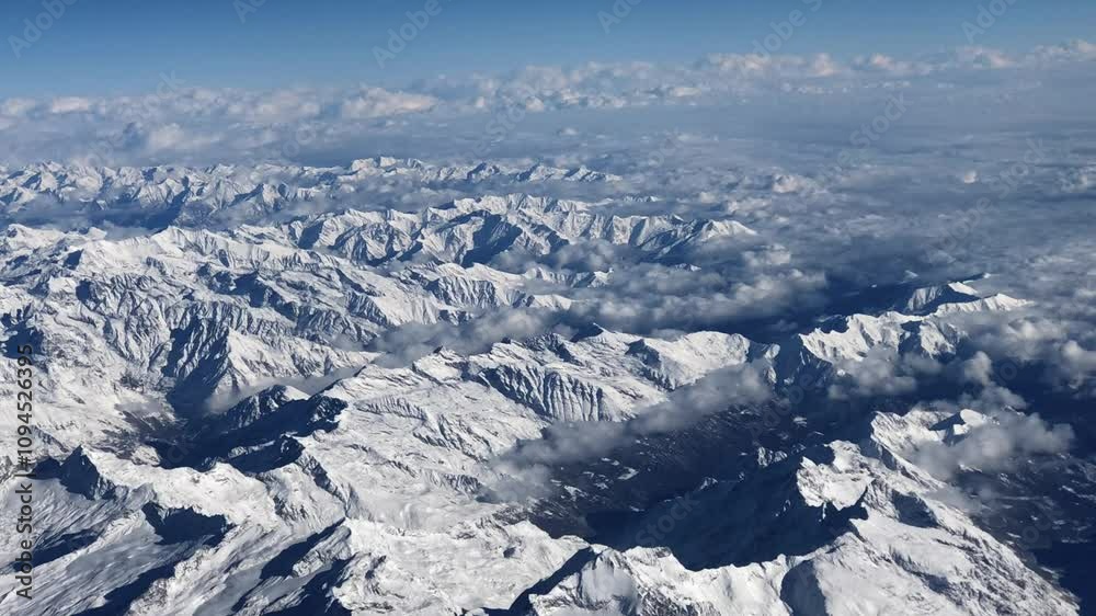 Magnificent panoramic hyperlapse of the Alps mountains viewed from the sky in winter, covered in snow and surrounded by clouds Magnificent panoramic hyperlapse of the Alps mountains viewed from the sky in winter, covered in snow and surrounded by clouds