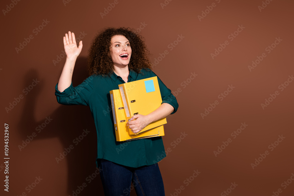Photo of shiny attractive lady dressed formal shirt holding papers folders waving arm empty space isolated brown color background Photo of shiny attractive lady dressed formal shirt holding papers folders waving arm empty space isolated brown color background