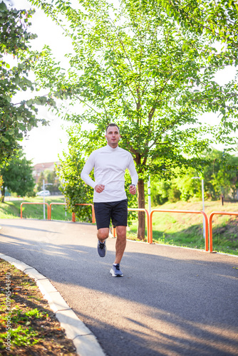 Young man running in the park during sunny autumn day