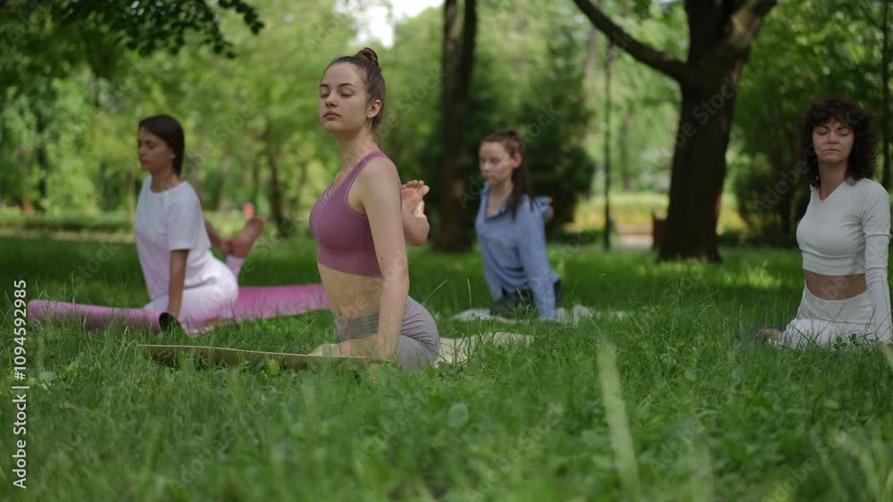 A group of women performing the Seated Spinal Twist pose during an outdoor yoga session in a lush park. This posture promotes flexibility spine health, and mindfulness in a serene natural environment A group of women performing the Seated Spinal Twist pose during an outdoor yoga session in a lush park. This posture promotes flexibility spine health, and mindfulness in a serene natural environment