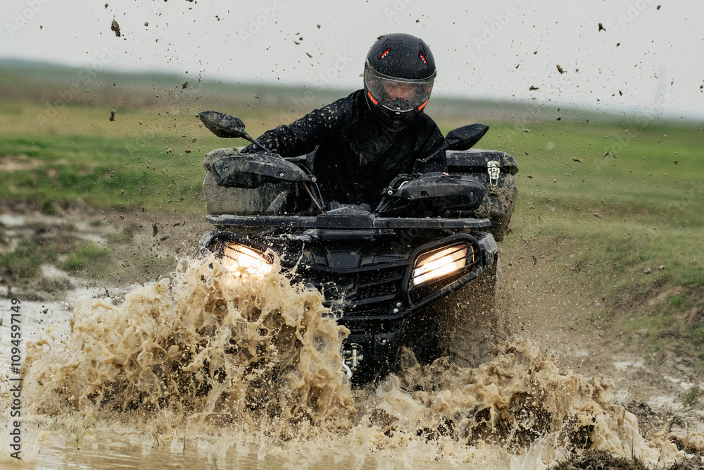 Rider splashes through mud on an all-terrain vehicle Rider splashes through mud on an all-terrain vehicle