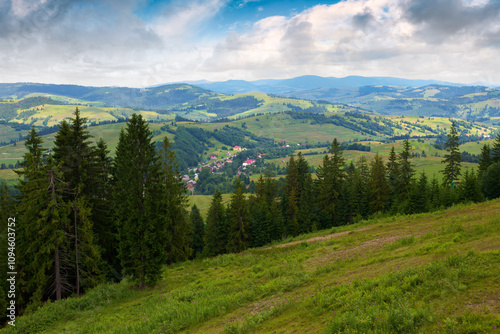 beautiful view of a countryside in carpathian mountains. alpine scenery. cloudy weather in summer. trees on the steep slope. village in the valley. dappled light. picturesque view