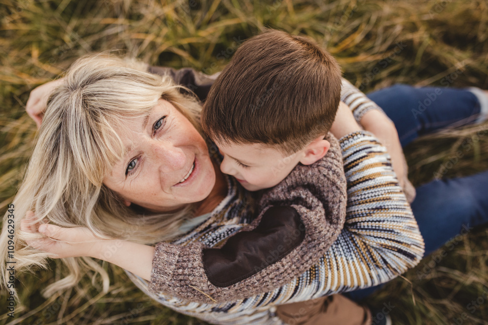 Fototapeta premium Grandmother hugging grandson outdoors autumn candid family portrait loving happy moment natural light cozy sweaters