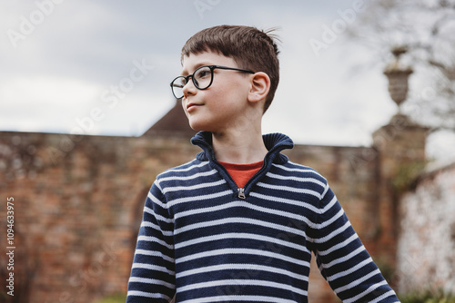 boy in stripey top wearing glasses contented looking to the side