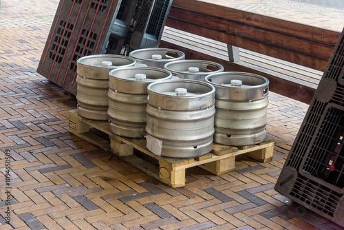 six metal beer barrels stand outside on a wooden industrial pallet photo