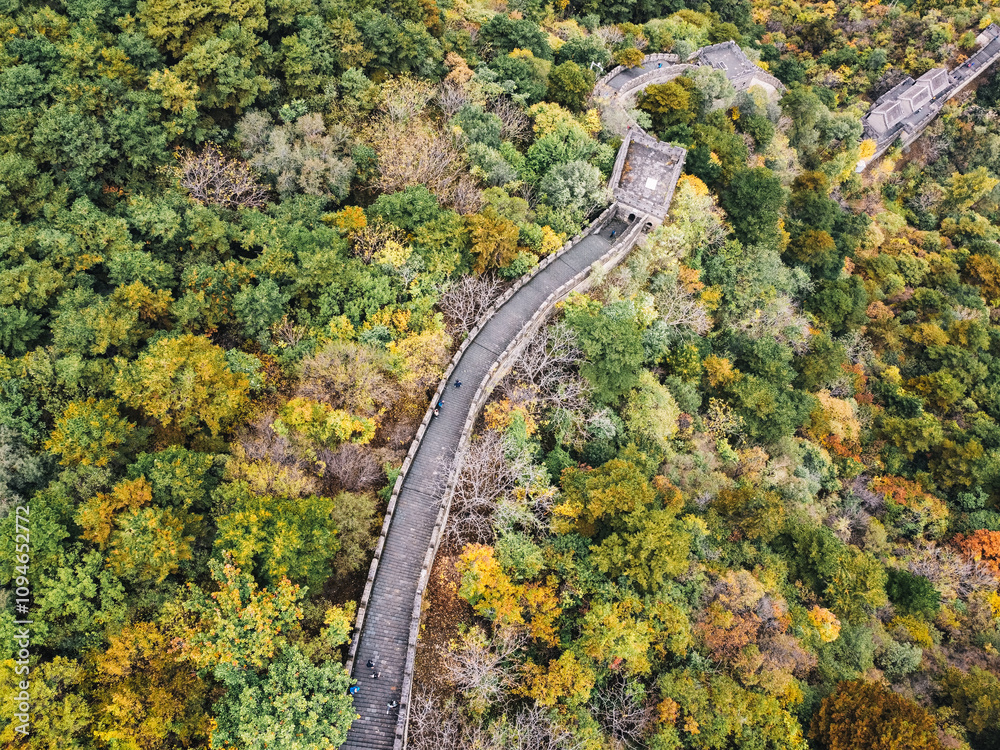 Aerial view of the Great Wall of China with autumn color leaves, a few tourists walking and a watchtower in Huairuou, near Beijing, China Aerial view of the Great Wall of China with autumn color leaves, a few tourists walking and a watchtower in Huairuou, near Beijing, China