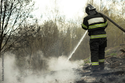 Firefighter puts out fire in woods. Lifeguard pours water.