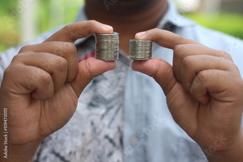 Bild auf Leinwand Hands compare two piles of coins of different sizes.